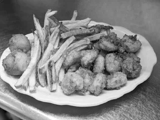 A plate of fried shrimp with hush puppies and hand-cut fries